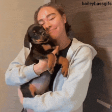 a woman is holding a puppy with the caption baileybassgifs above her
