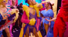 a group of drag queens are standing next to each other in colorful costumes .