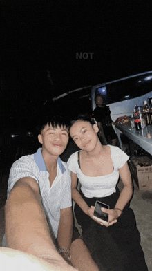 a man and a woman are posing for a picture with the word not visible in the background