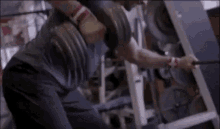 a man is squatting with a dumbbell on his back in a gym .