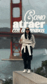 a woman stands on a wall in front of the golden gate bridge with the words como atraer con contenidos
