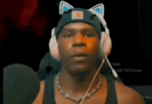 a man wearing headphones and a beanie with cat ears is talking into a microphone .