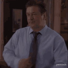 a man in a blue shirt and tie with his arms crossed
