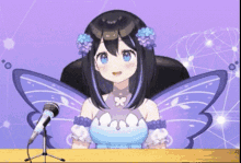 a girl with butterfly wings is sitting at a desk with a microphone