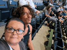 a man and a woman are sitting in a stadium with a man making a face