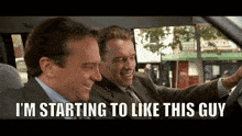 two men in suits are sitting in a car and one of them is saying i 'm starting to like this guy