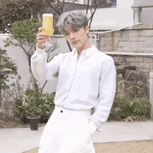 a young man in a white shirt is holding a glass of beer