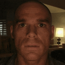 a man with a shaved head looks at the camera