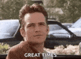 a man is sitting in a car with a car in the background and says `` great times '' .