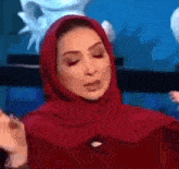 a woman wearing a red hijab is making a face .