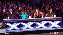 a group of people are sitting in front of a sign that says xxx