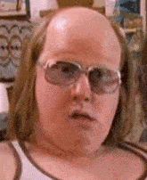 a bald man wearing glasses and a tank top .