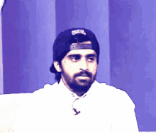 a man with a beard wearing a hat that says ' gsbl ' on it