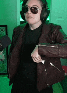 a woman wearing sunglasses and headphones is taking off her jacket