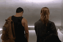 a man and a woman are standing in an elevator with their backs to the camera
