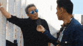 a man wearing sunglasses is being interviewed by a young man