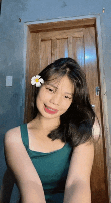 a young woman with a flower in her hair looks at the camera