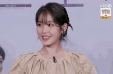 a woman smiles in front of a sign that says kbs