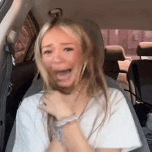 a woman sitting in the back seat of a car making a funny face