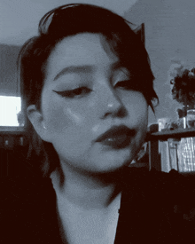 a black and white photo of a woman 's face in front of a bookshelf