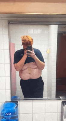 a man taking a selfie in front of a mirror with a purell dispenser