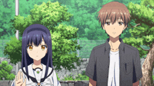 a boy and a girl are standing next to each other with trees in the background