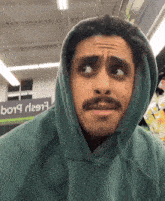 a man wearing a green hoodie is standing in front of a sign that says b019