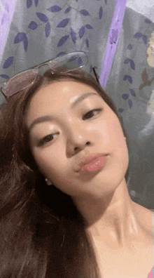 a young woman wearing sunglasses is taking a selfie in front of a window .