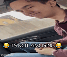 a man is sitting in the back seat of a car with a caption that says ts not amusing .