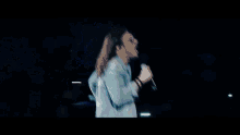 a man singing into a microphone with a crowd behind him