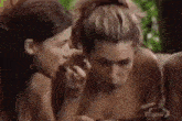 a group of naked women are eating food together in the jungle .