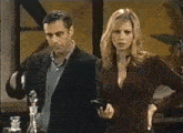 a man in a suit is pouring a cup of coffee into a woman 's mouth