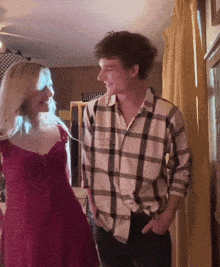 a man in a plaid shirt and a woman in a red dress are standing next to each other and smiling