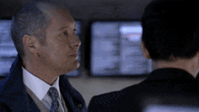 a man in a suit and tie is looking at another man