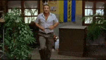 a man in a white shirt is running in a room with a blue and yellow flag on the wall .