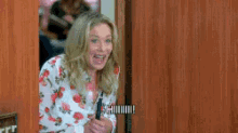 a woman is peeking out of a wooden door and smiling .
