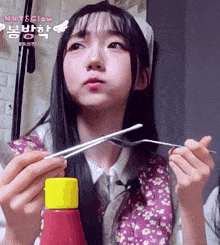a girl is holding chopsticks and a bottle of ketchup with the words next & glow on the bottom