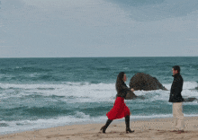 a man and a woman dancing on a beach near the ocean