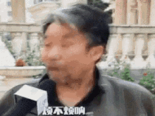 a man is talking into a microphone and making a face .