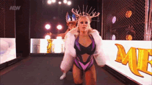 a woman in a fur coat is walking down a ramp with a sign that says aew on it .