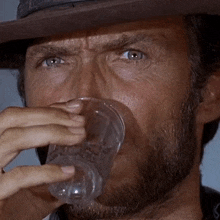a man with a beard is drinking out of a clear plastic cup