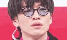 a close up of a man wearing glasses and a earpiece