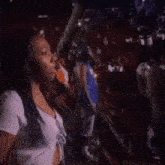 a woman in a white shirt is standing in front of a crowd of people