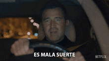 a man driving a car with the words es mala suerte written on the screen