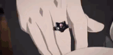 a close up of a person 's hand with a black cat ring on it .