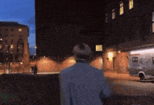 a man walking down a street with an ambulance parked in front of him
