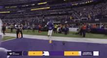 a football player in a purple uniform is running on a field .