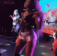 a woman is dancing on a stage in a club with purple lights behind her .
