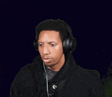a man wearing headphones and a black shirt looks at the camera