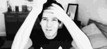 a black and white photo of a man with his hands on his head .